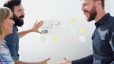 Mutlu meslektaşlar yeni bir projenin mali istatistiklerini tartışıyor.