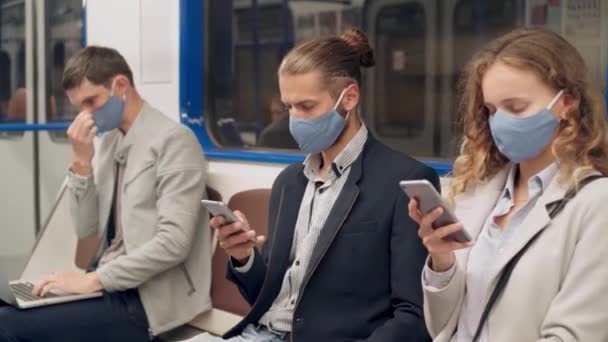 Молодь в захисних масках використовує свої смартфони в машині метро . — стокове відео