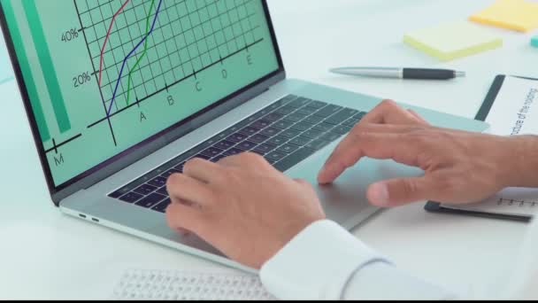 Człowiek analizuje biznesowe wykresy na laptopie. — Wideo stockowe