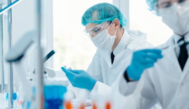 Kapat. Laboratuvar masasında oturan bir grup bilim adamı..