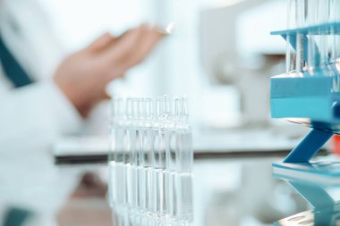 Tıp laboratuarındaki masanın üstünde aşı şişeleri var..