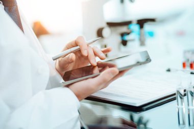 Yakın plan. Bilim adamı dijital tabletinde notlar okuyor..