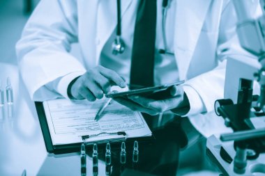 Dijital tabletli bir bilim adamı araştırma notlarına bakıyor..