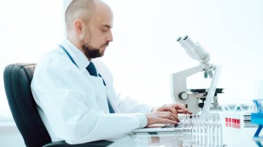 Tıp laboratuarında dizüstü bilgisayar kullanan bir bilim adamı..