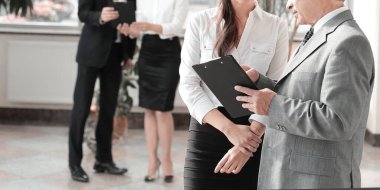 İş adamı ve asistan modern ofiste çalışan kağıtları tartışıyor