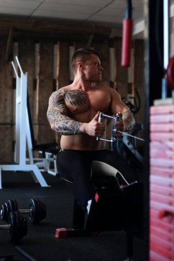 Vücut geliştirici spor salonundaki bir simülatörde egzersiz yapıyor..