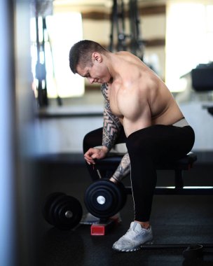 Vücut geliştirici spor salonunda dambıllarla egzersiz yapıyor..