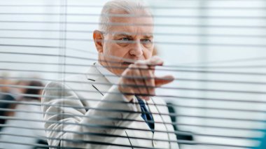 gülümseyen olgun iş adamı ofis penceresinden bakıyor..