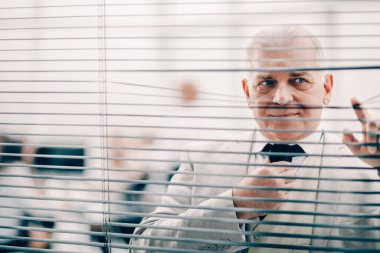 Kapat. Ofis penceresinin önünde duran ciddi bir iş adamı.