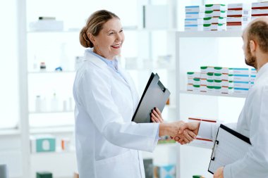 Dost canlısı kadın eczacı yeni bir çalışanla el sıkışıyor..