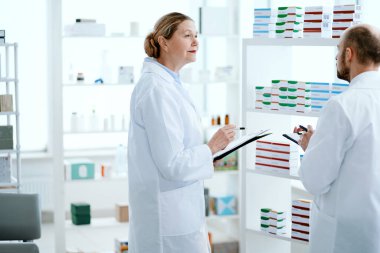 İki eczacı adam ve kadın konuşuyor, ilaçları tartışıyorlar..