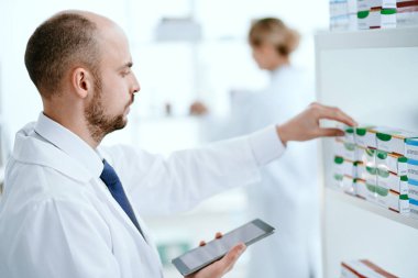 Dijital tabletli eczacı internetten sipariş vermek için ilaç seçiyor..