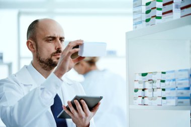 Eczacı dijital tabletinin ekranından bilgileri okuyor..