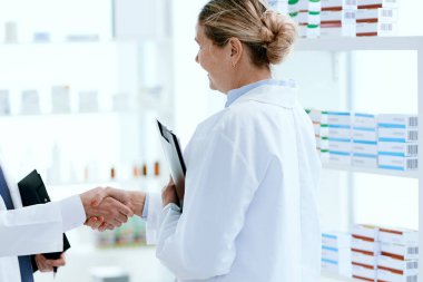 Bayan eczacı meslektaşıyla el sıkışıyor..