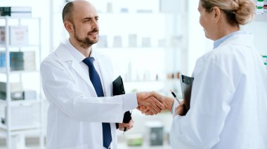 Erkek eczacı iş arkadaşıyla el sıkışıyor..