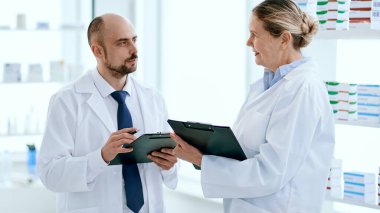 İki eczacı adam ve kadın konuşuyor, ilaçları tartışıyorlar..