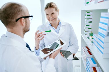 Erkek ve kadın eczacılar yeni ilaçlarını tartışıyor. .