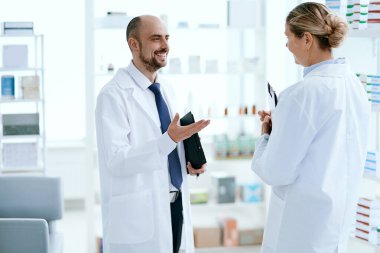 Üst düzey eczacı meslektaşıyla bir şey tartışıyor..