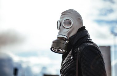 Boş bir şehirde sokakta duran gaz maskeli sıradan bir genç adam.