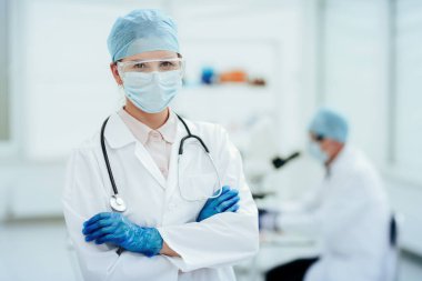 Kapat. Koruyucu giysili kadın doktor laboratuvarda duruyor..