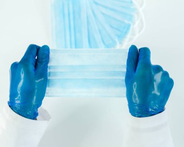 Kapat. Doktorun elinde koruyucu maske.