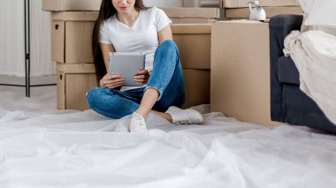 Genç bir kadın yeni dairesinde dijital tablet kullanıyor.