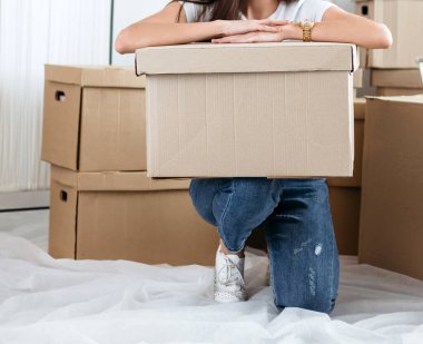 Karton kutulu genç bir kadın yeni bir dairede yerde oturuyor.