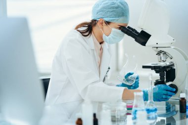 Kapat. Kadın bilim adamı mikroskoptan bakıyor..