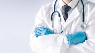 Koruyucu maske takan ve eldiven takan doktor kendine güvenen bir şekilde sana bakıyor..