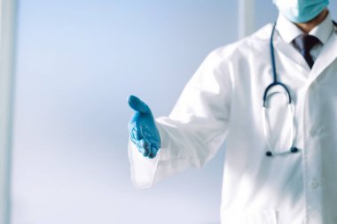 Steteskoplu bir doktor el sıkışmak için elini uzatıyor. .