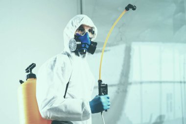 Dezenfekte hizmetleri çalışanı kişisel koruyucu ekipman giyiyor, dezenfektan püskürtüyor..