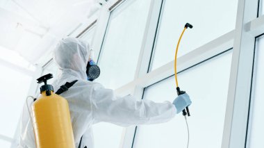 Bakteriyolojik koruma giysisi giyen temizlik işçisi ofiste çalışıyor. .