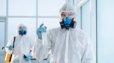 Odada bir şişe antiseptik taşıyan genç bir dezenfektan var. .