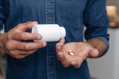 Genç adam hapları avucunun içinde tutuyor..