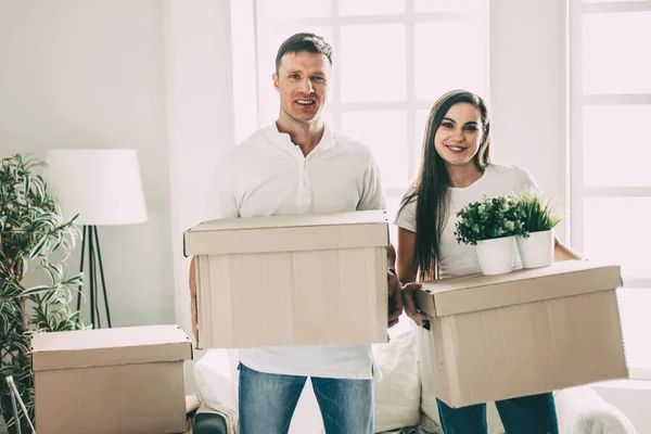 young couple with cardboard boxes standing in a new apartment.