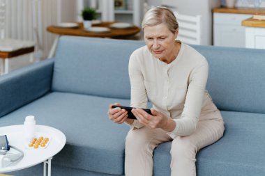 Yaşlı kadın akıllı telefonunun ekranına bakıyor. .