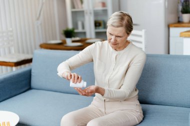 Yaşlı kadın elindeki haplara bakıyor. .