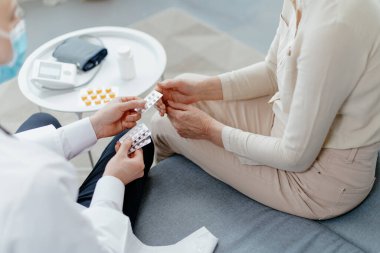 Doktor oturma odasında yaşlı bir kadına danışıyor..