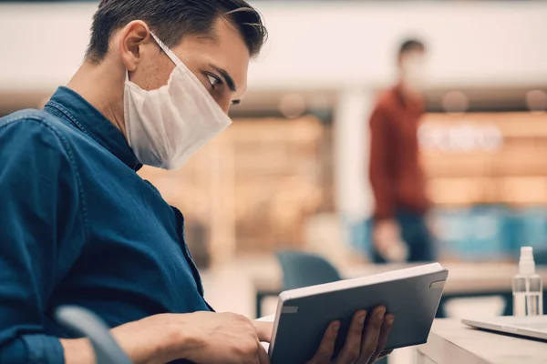 Junger Mann liest ein Buch und sitzt an einem Tisch im Food Court — Stockfoto