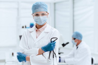 Steteskopu olan ciddi bir kadın doktor bir tıp laboratuarında duruyor. .