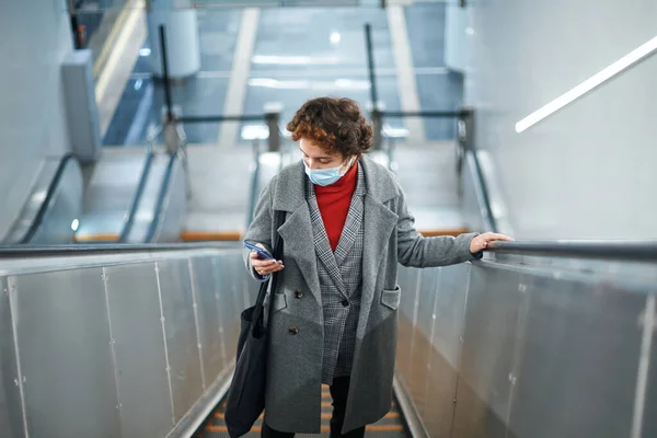 Frau liest SMS auf der Rolltreppe . — Stockfoto