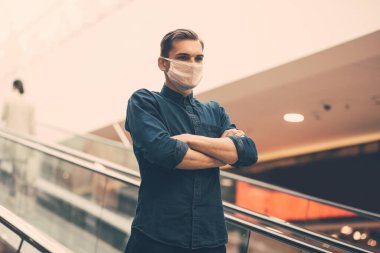 Korumalı maskeli bir adam metro yürüyen merdiveninin basamaklarında duruyor..