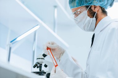 Kapat. Laboratuvar çalışanı laboratuvar masasında oturuyor.