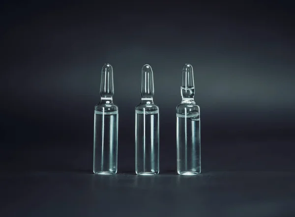 Ampollas de vidrio medicinal sobre un fondo oscuro. —  Fotos de Stock