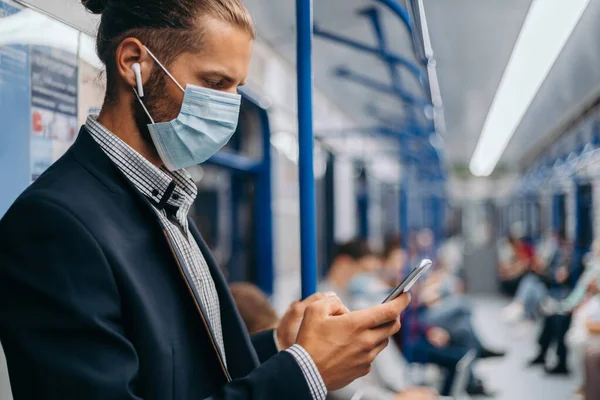Homem com uma máscara protetora de pé em um carro de metrô. — Fotografia de Stock