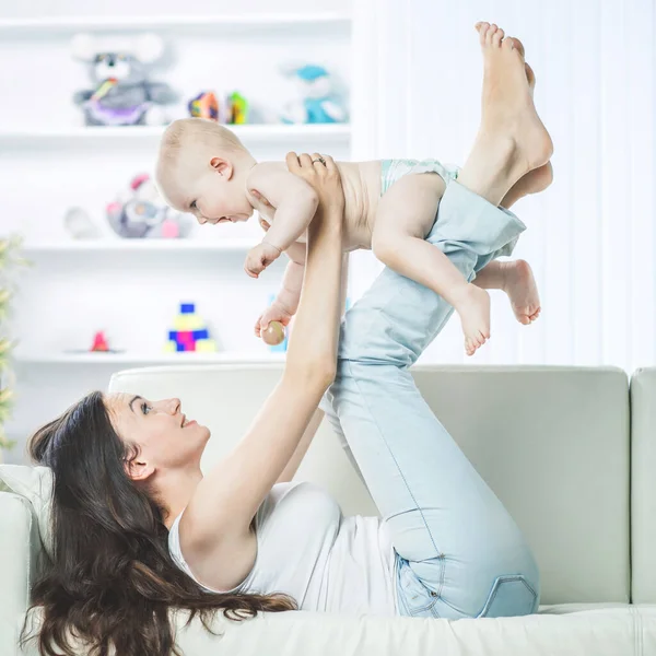 Concepto de maternidad: madre feliz jugando con un bebé de un año en la habitación para los niños — Foto de Stock