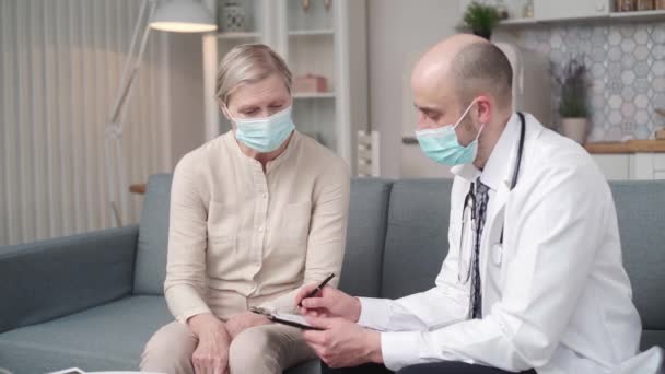 Doctor filling out a medical form during a home visit. — Stock Video