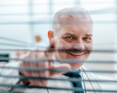 Gülümseyen başarılı iş adamı perdelerden bakıyor..