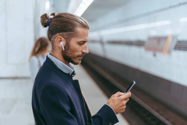 Metroyu beklerken akıllı telefonlu bir iş adamı..