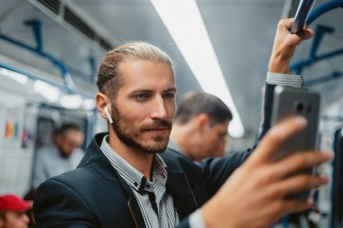 Metroda akıllı telefonunu kullanan çekici bir adam. .